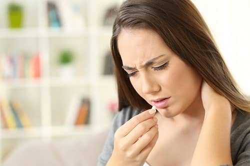 Женщина пьет таблетки от мигрени